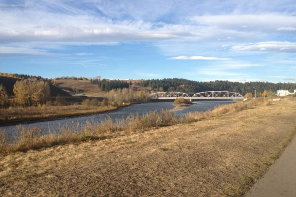 Riverside landscape with a bridge, grassy bank, and blue sky on a sunny day