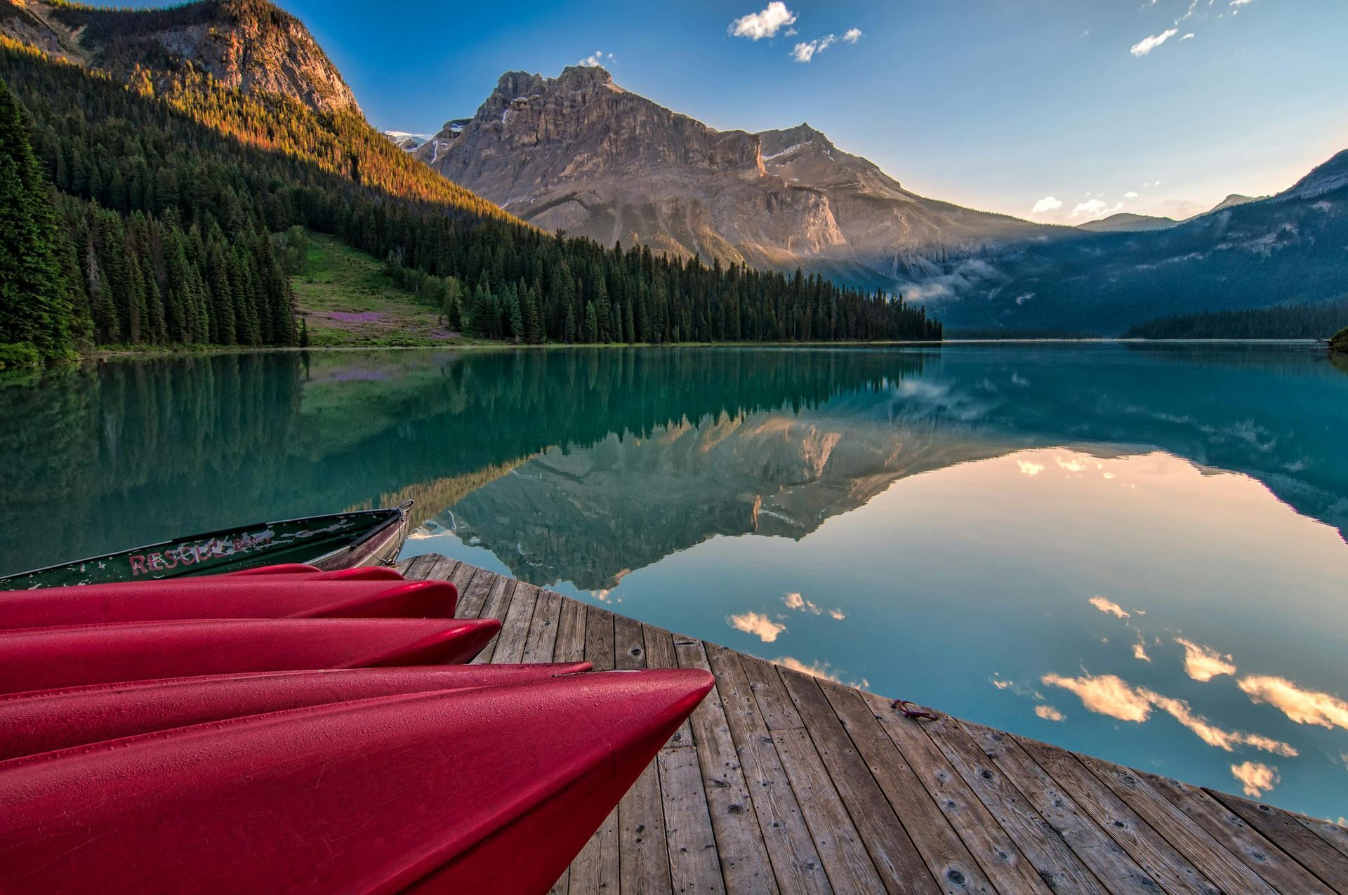 Panoramic view of the Rocky Mountains with a turquoise lake and dense forest.