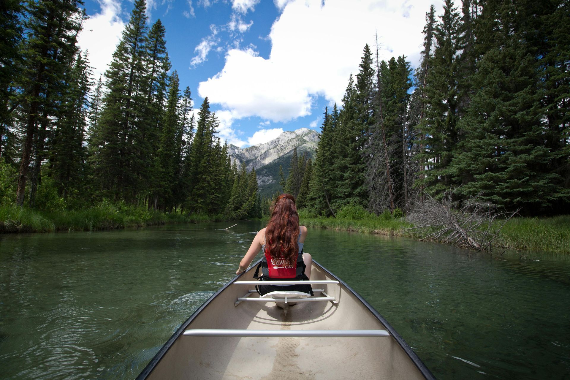 Person paddling a canoe on calm waters.