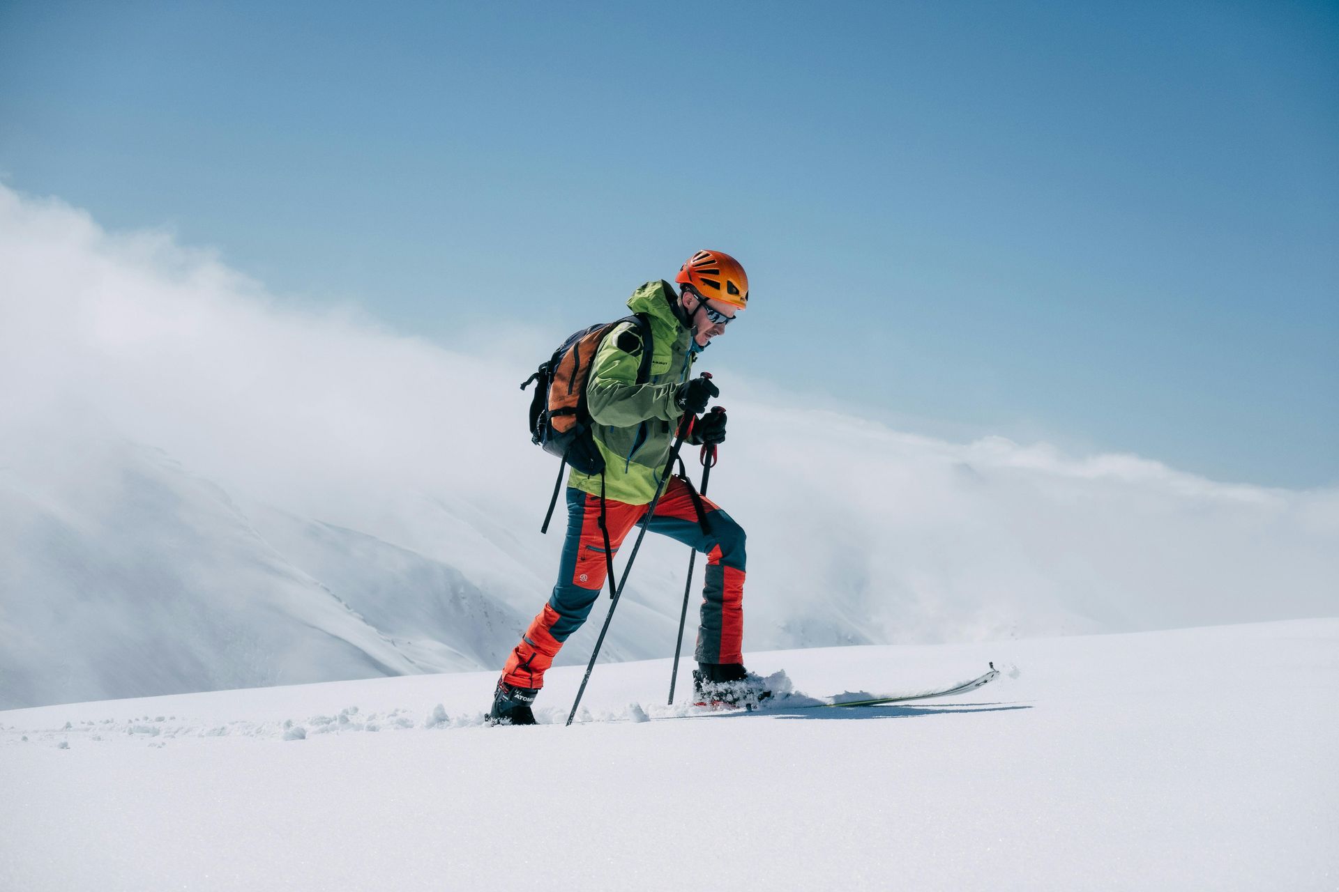 Snowshoer walking through fresh snow with ski poles.