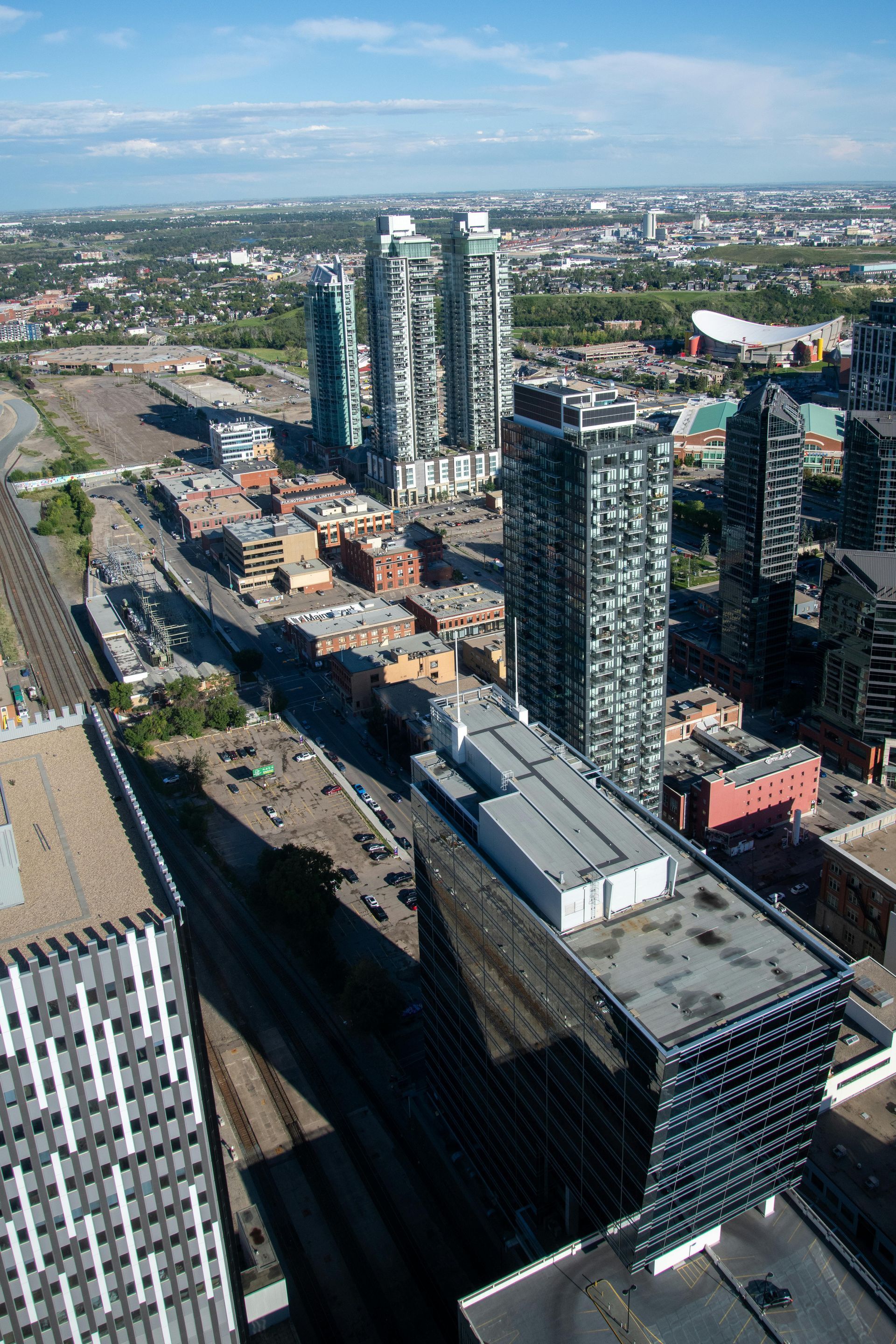 Aerial view of Calgary cityscape with skyscrapers, streets, and a blue sky.