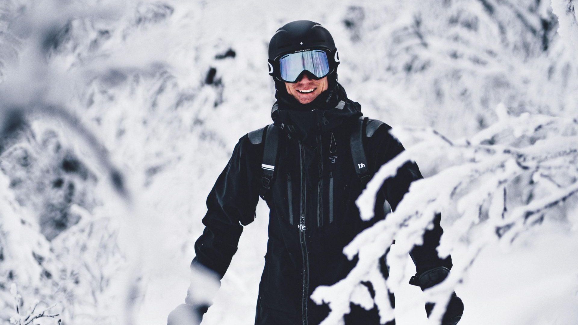 A red pedestrian bridge over a partially frozen river, with a city skyline in the background on a cloudy day.
