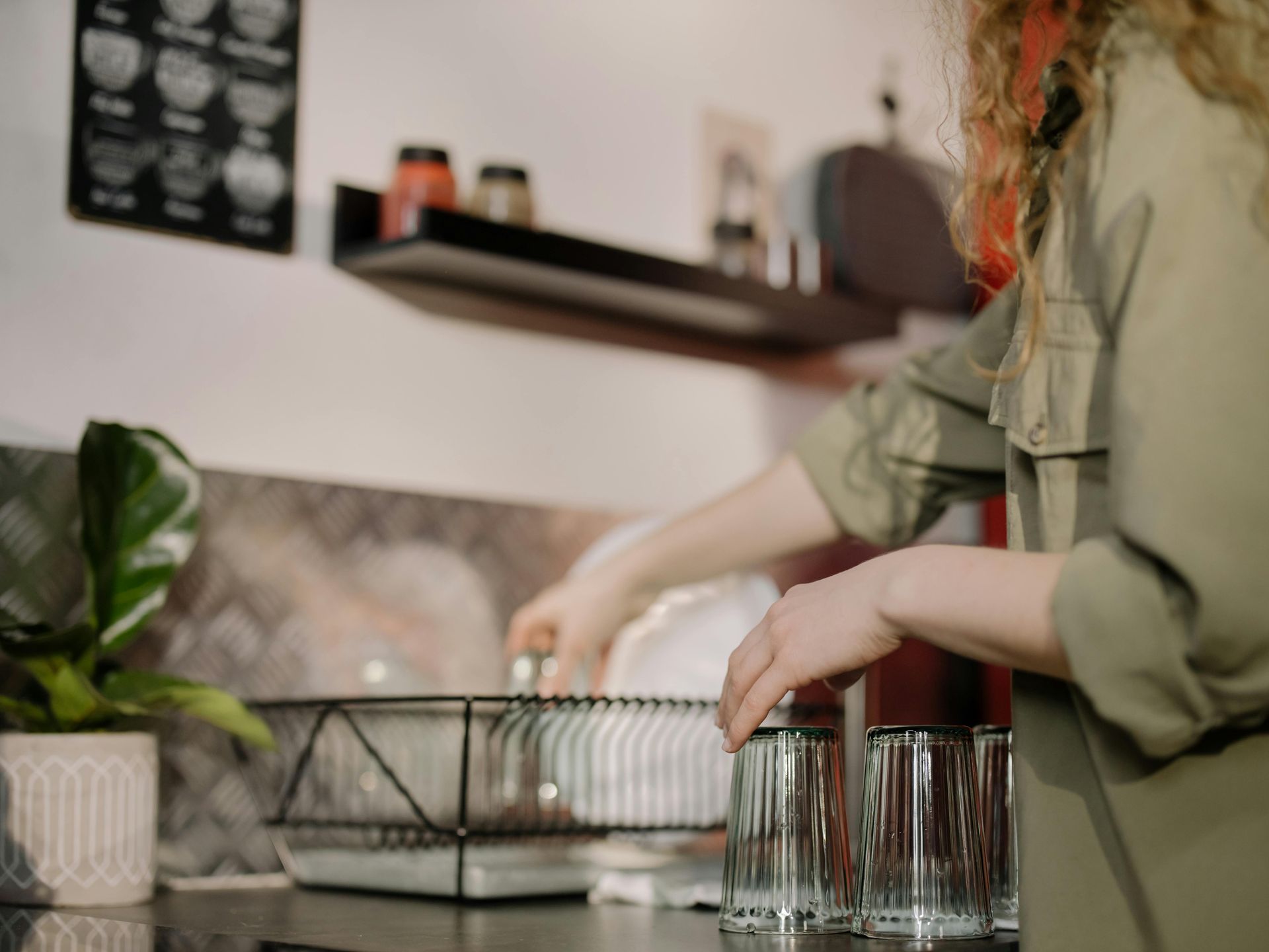 A woman is washing dishes in a kitchen.