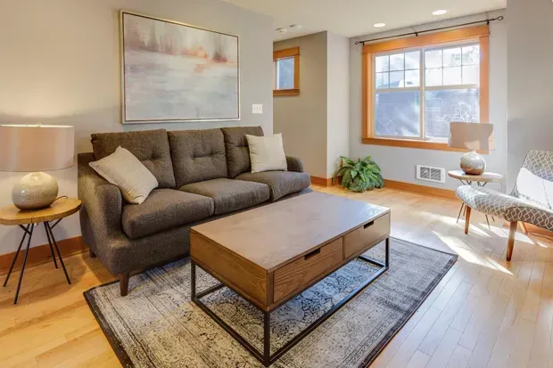 A living room with a couch , chair , coffee table and rug.