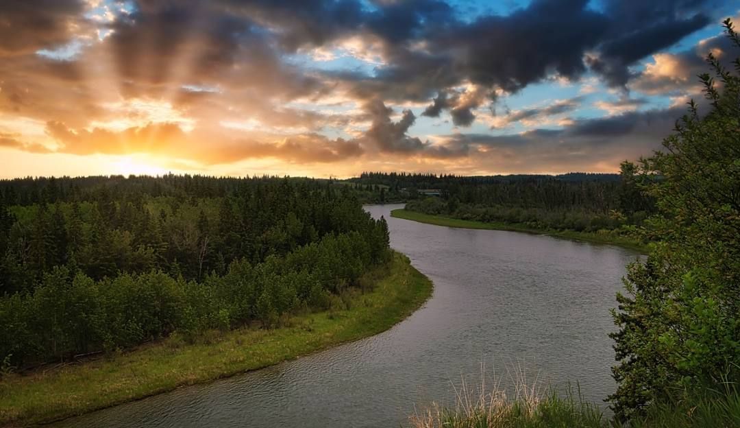 A woman is paddling a red kayak on a river.