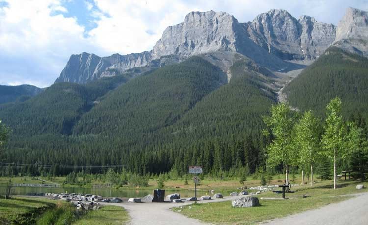 Mountain landscape with green forest, light path, and blue sky.