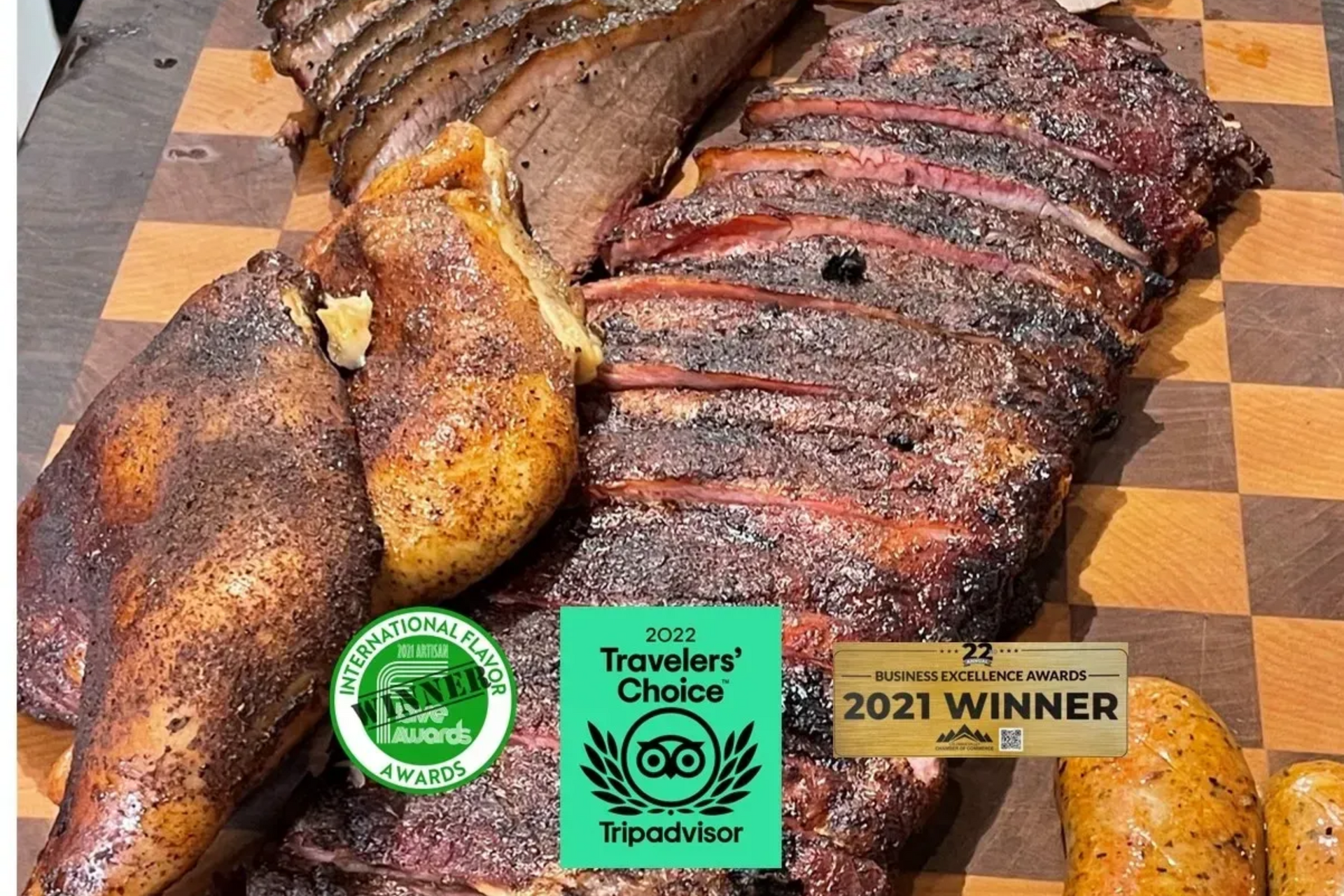 Smoked meats on a checkerboard cutting board with award badges and a 2021 winner label