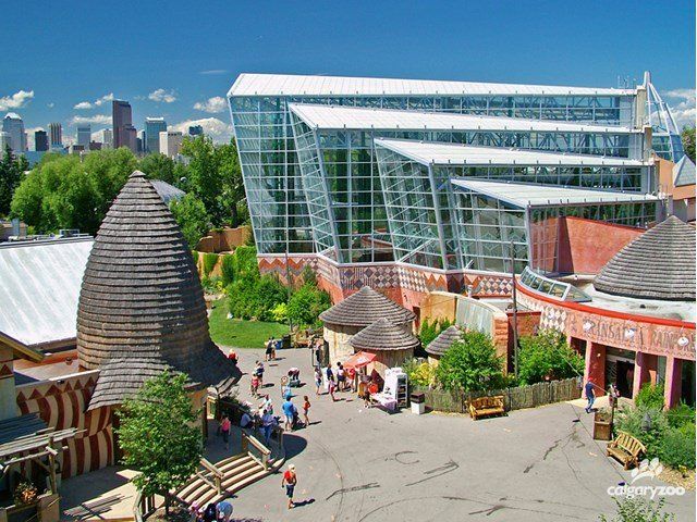 An aerial view of a zoo with a large glass building in the background