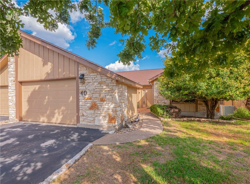 A house with two garages and a tree in front of it.