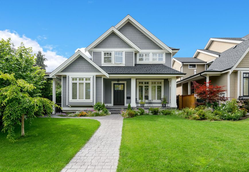 A large house with a lush green lawn and a walkway leading to it.