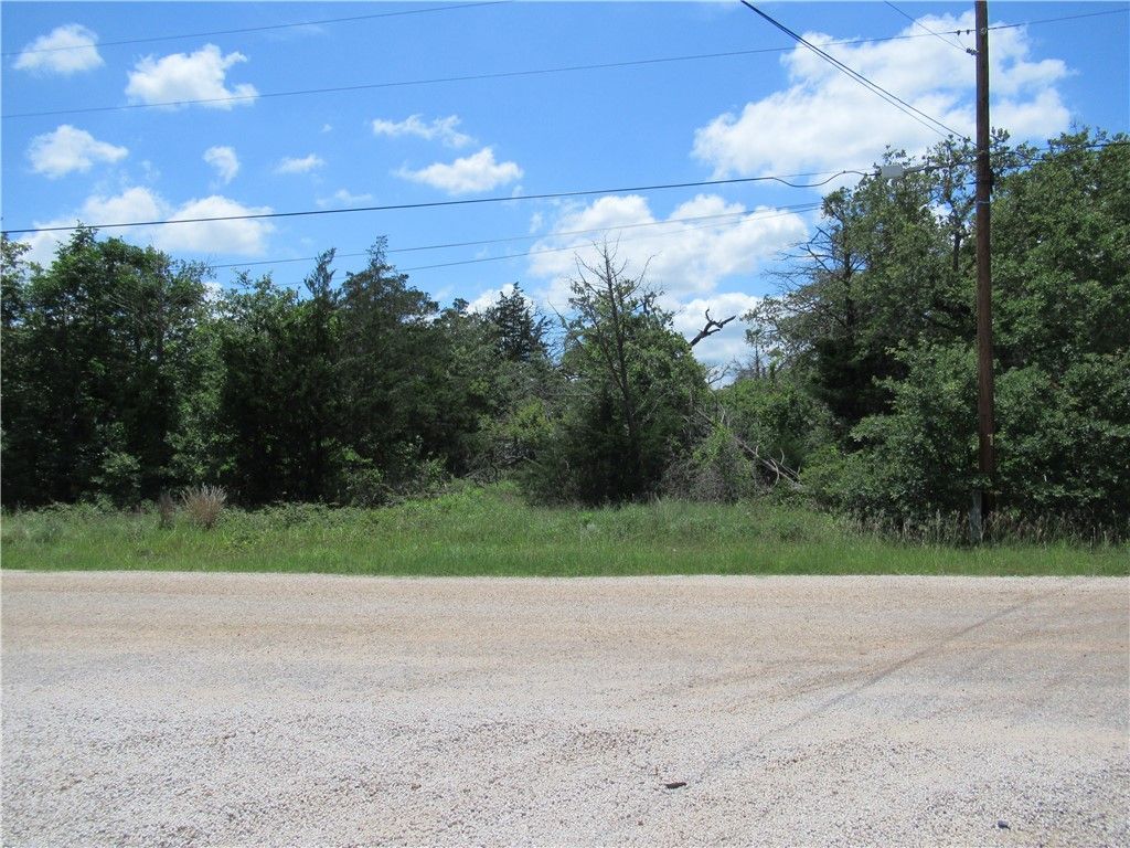 A dirt road with trees in the background and a blue sky