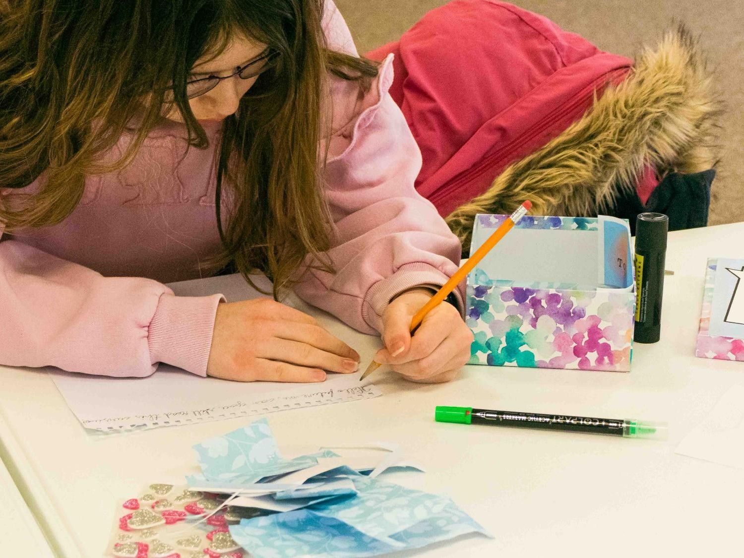 Alphabet soup participant writing a letter for their time capsule box