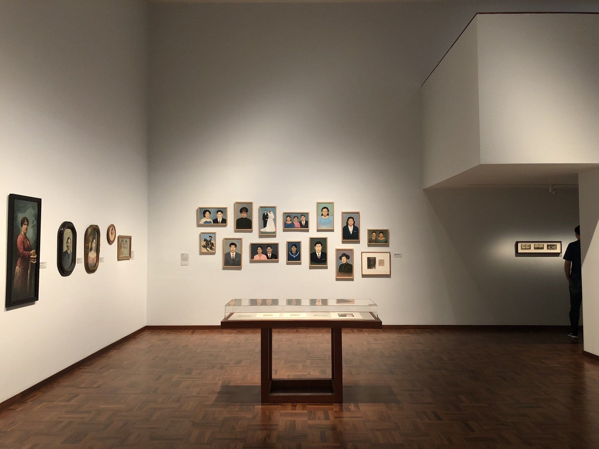 Un hombre está en un museo mirando pinturas en la pared.