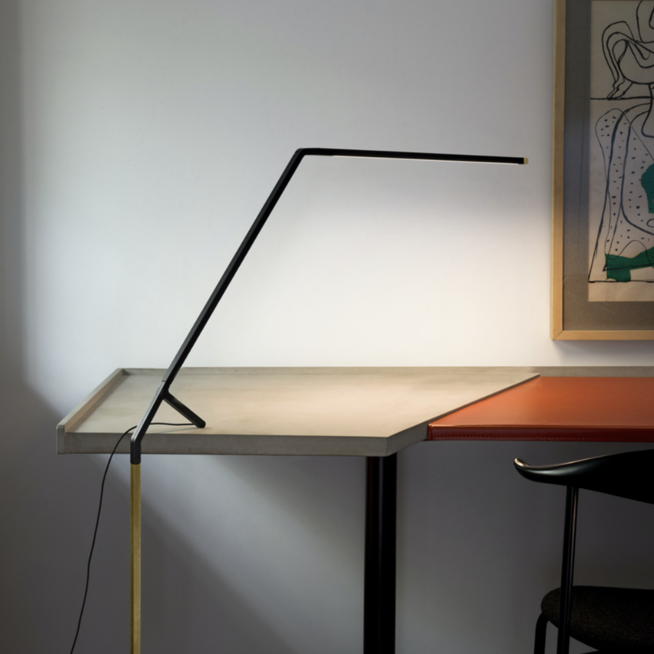 Un escritorio con una lámpara encima y un cuadro en la pared encima.