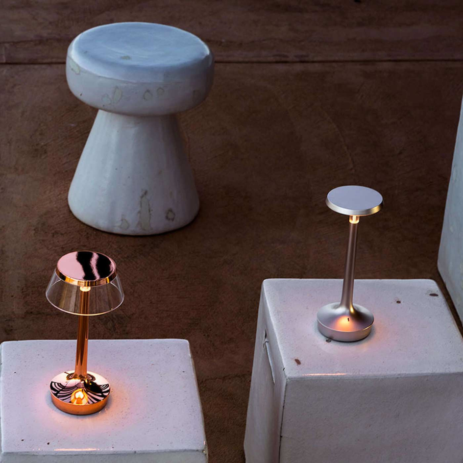 Dos lámparas están encendidas al lado de un taburete blanco.