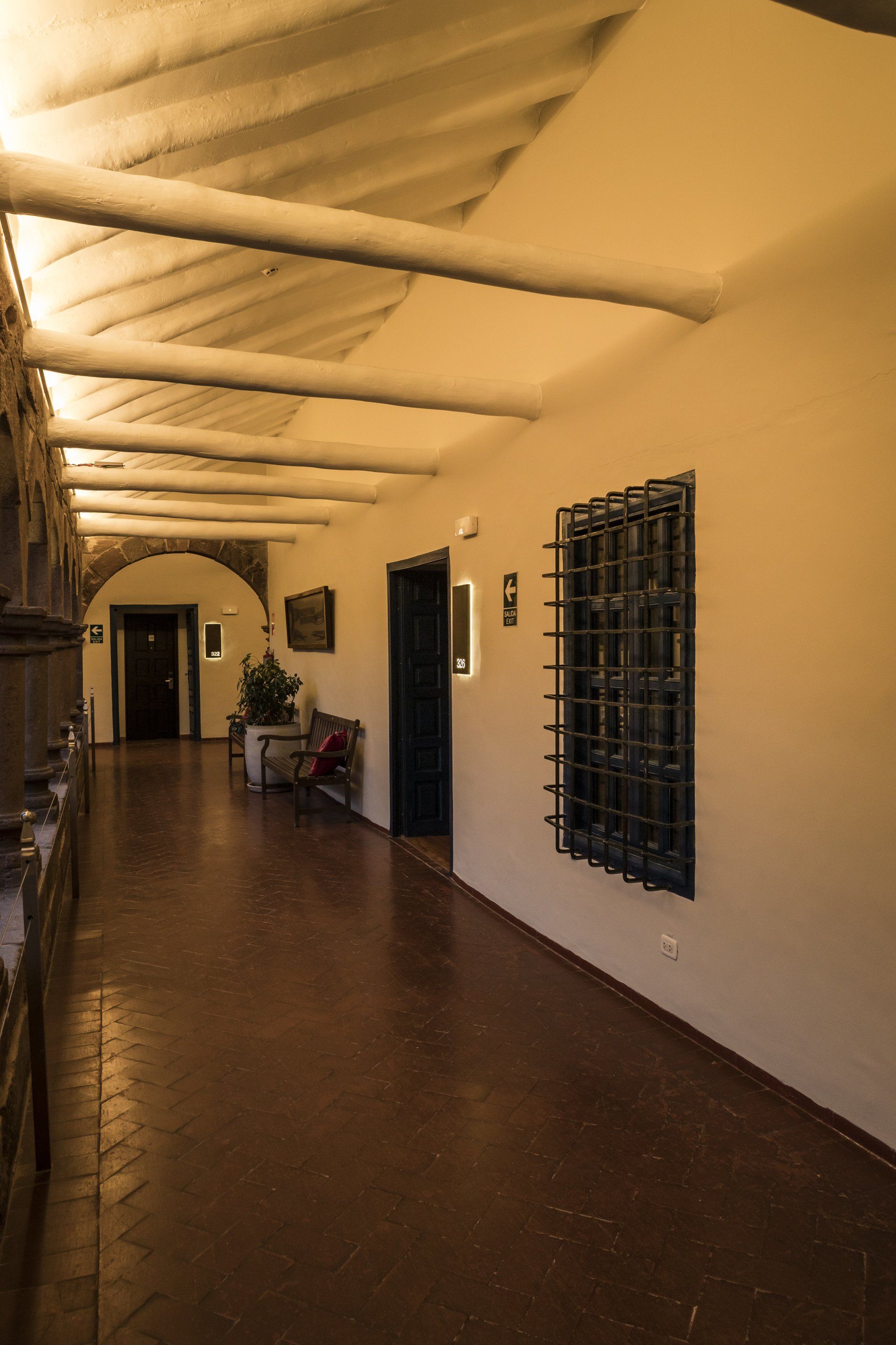 Un pasillo largo con un banco y una ventana en un edificio.