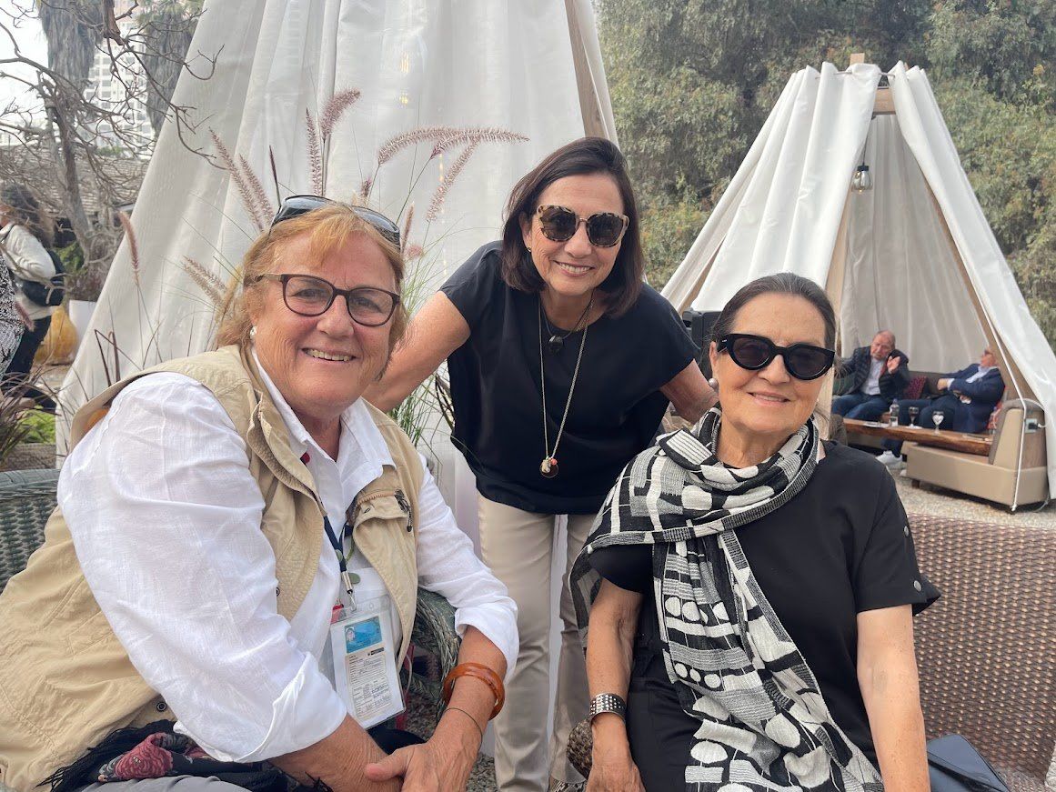 Tres mujeres posan para una fotografía delante de una tienda de campaña.