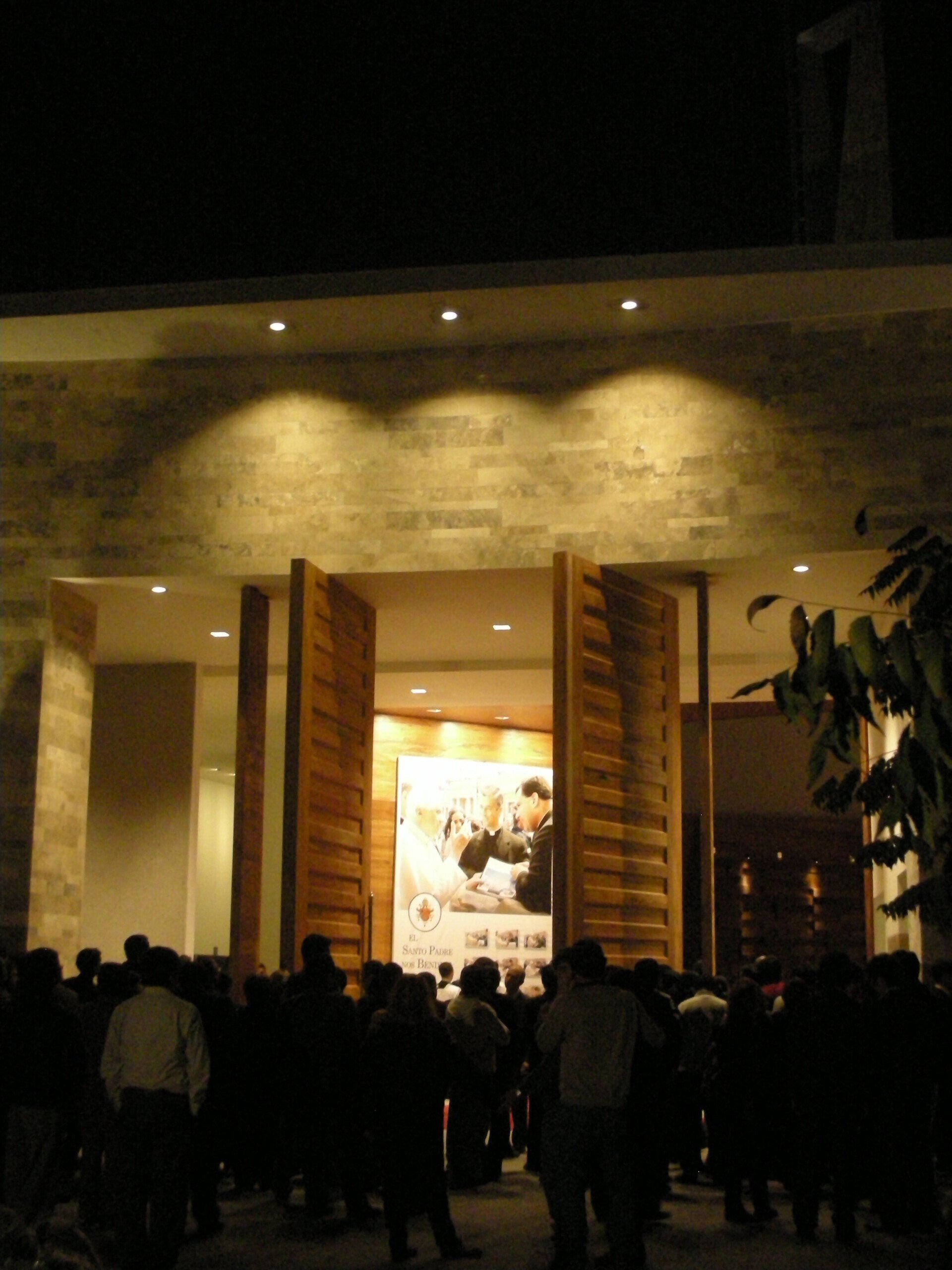 Un grupo de personas paradas afuera de un edificio por la noche.