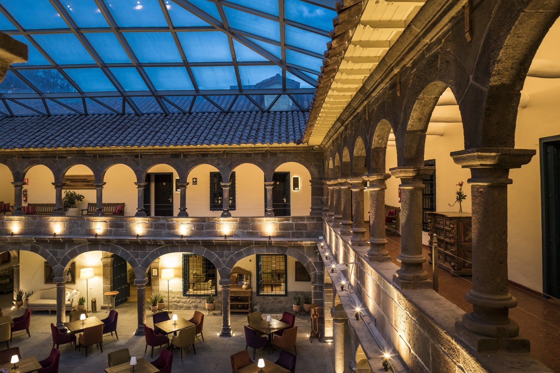 Una vista aérea de un edificio con arcos y mesas y sillas.