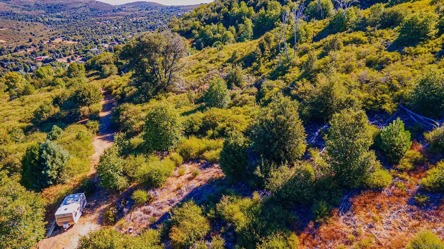 A white SUV on a dirt road winding through dense green hills and forest.