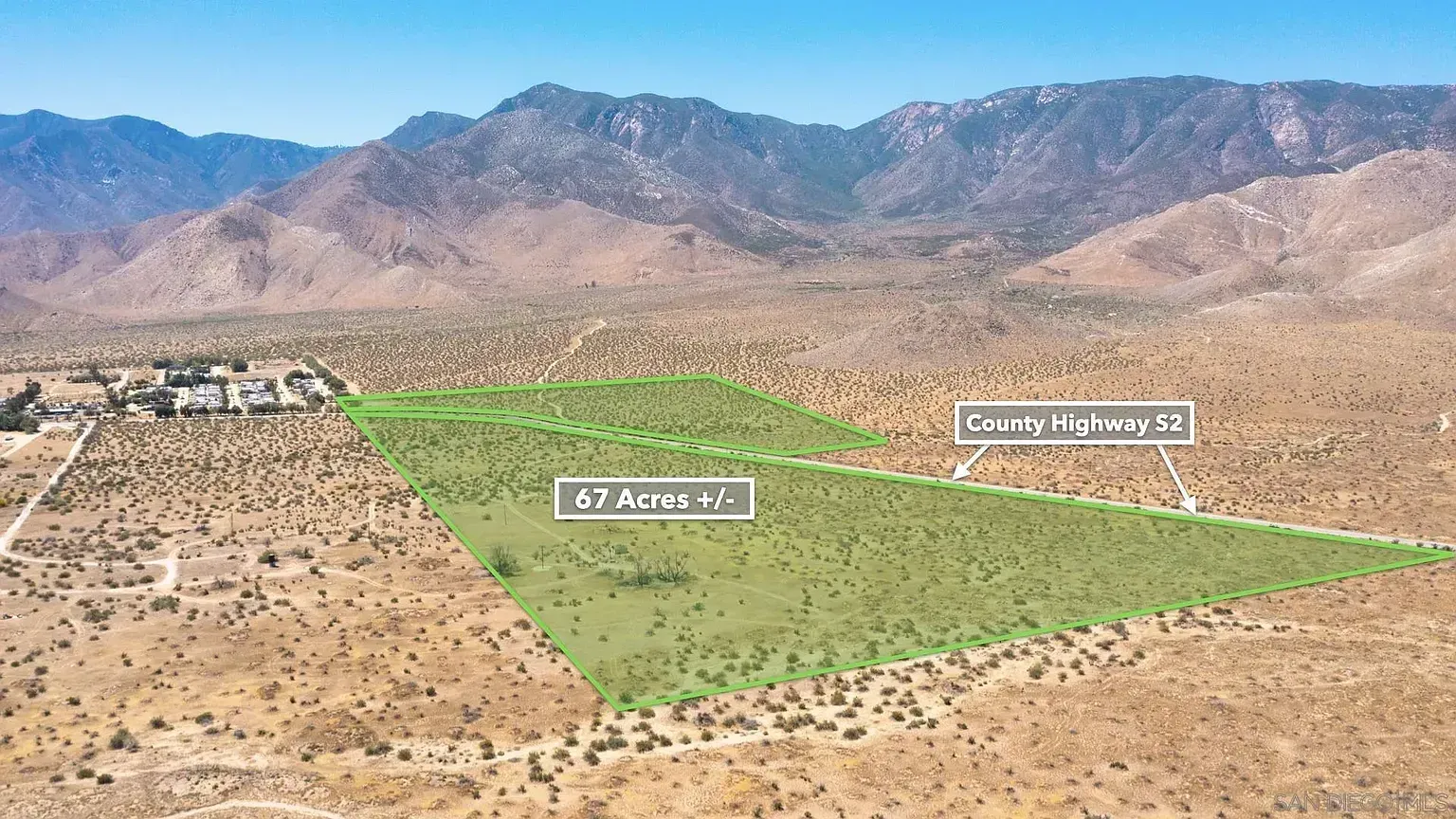 Desert valley with a green highlighted parcel and mountain range in the background.
