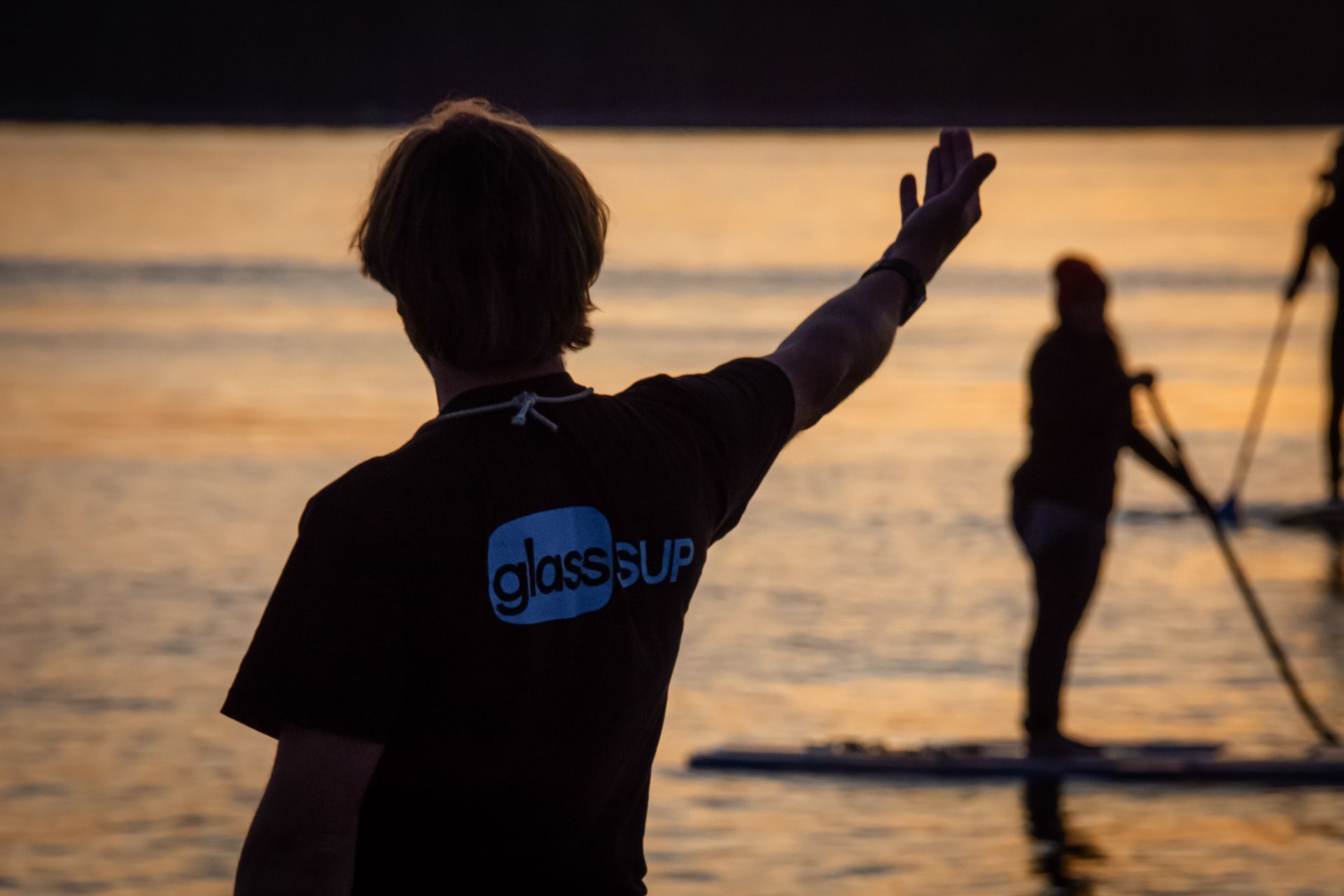 Ein Mann mit einem glassSUP -Shirt steht im Wasser und winkt