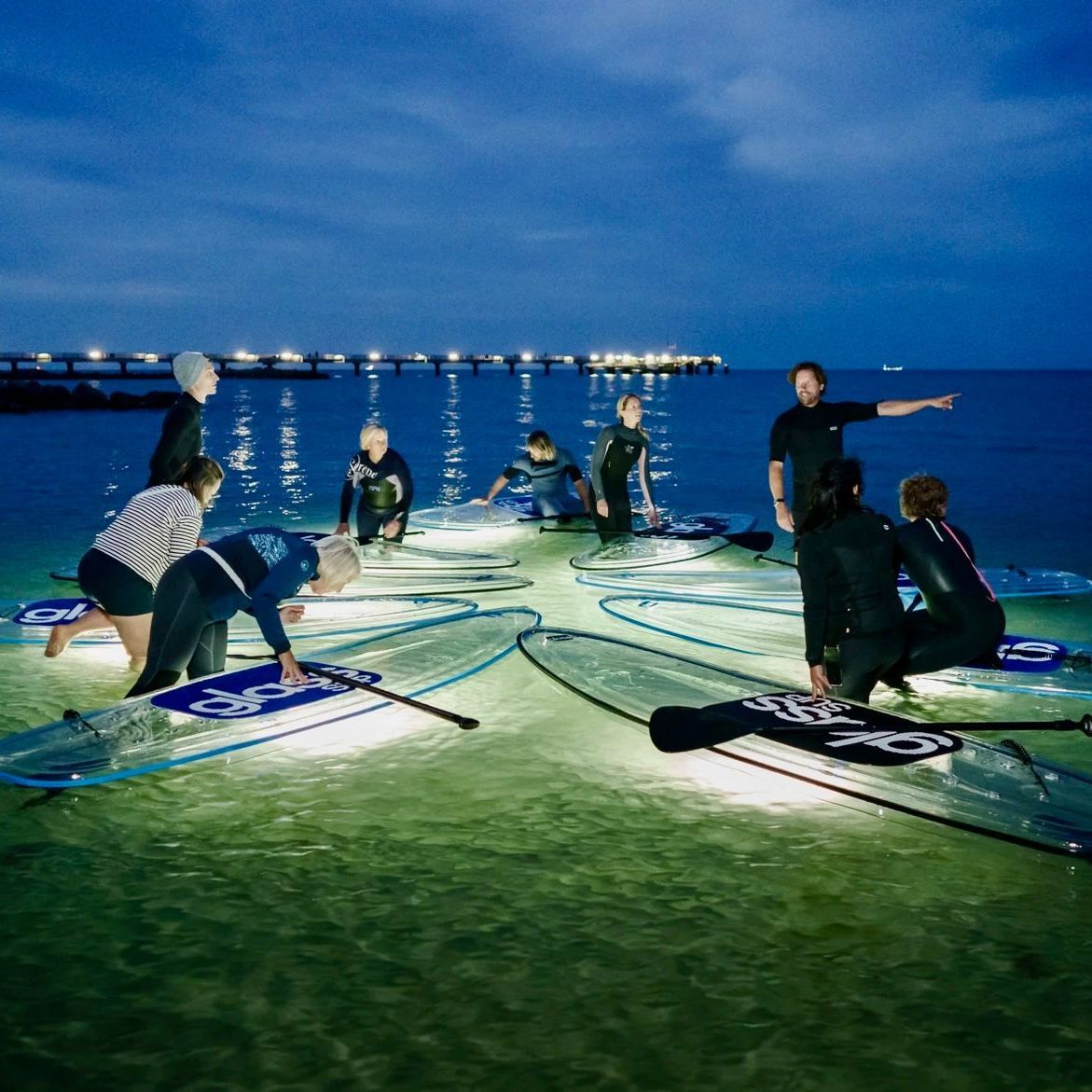 Eine Gruppe von Menschen sitzt auf glassSUPs im Wasser