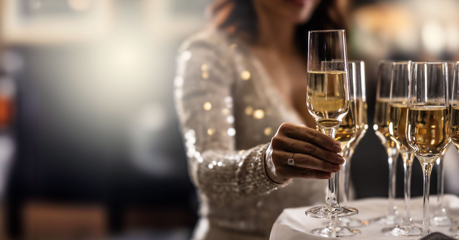 Una donna tiene in mano un bicchiere di champagne in un ristorante.