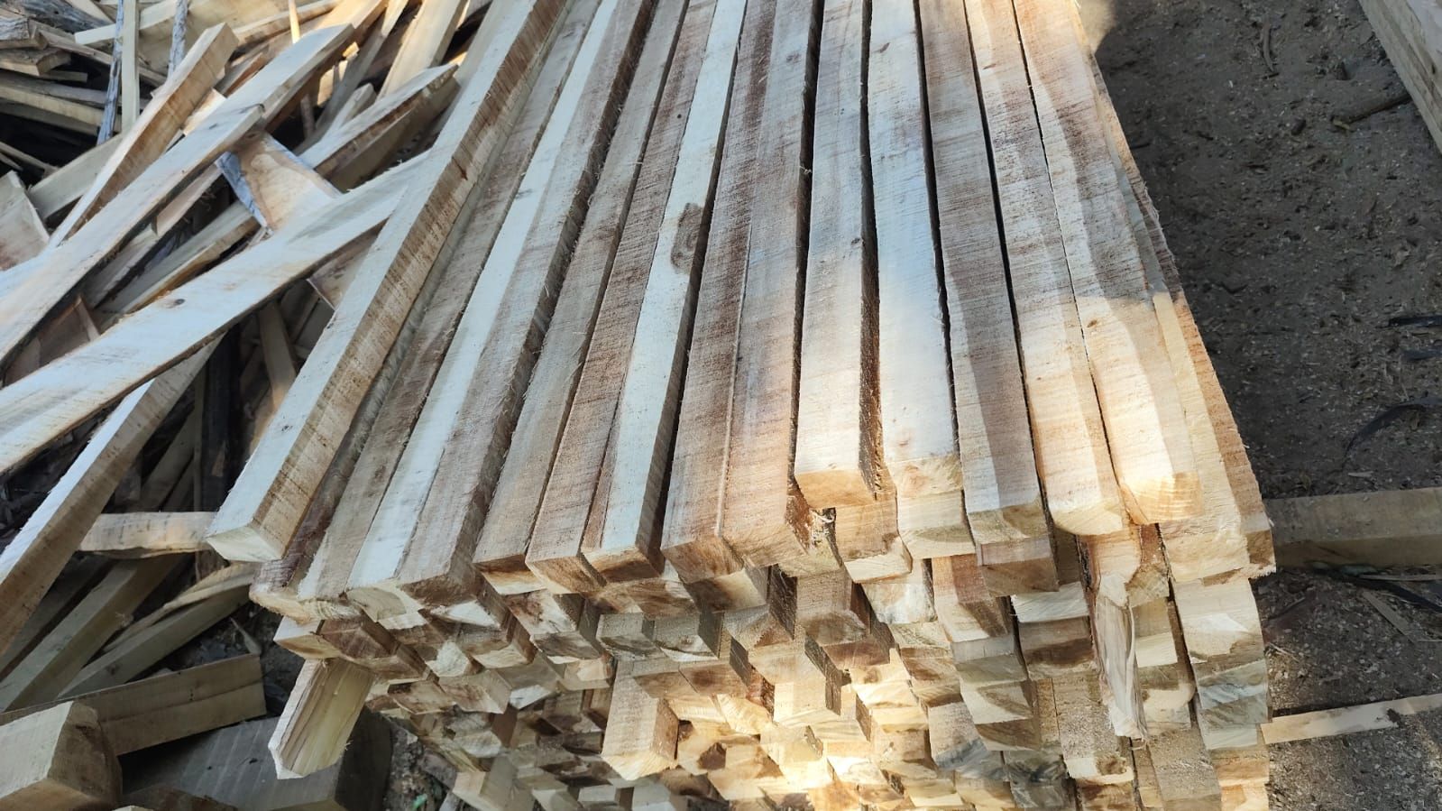 Pila de tablones de madera de distintos tamaños, apilados al aire libre.