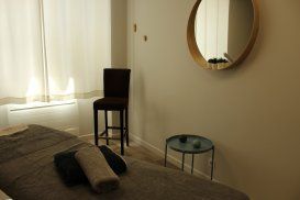 Une chambre avec un lit, une chaise, une table et un miroir.