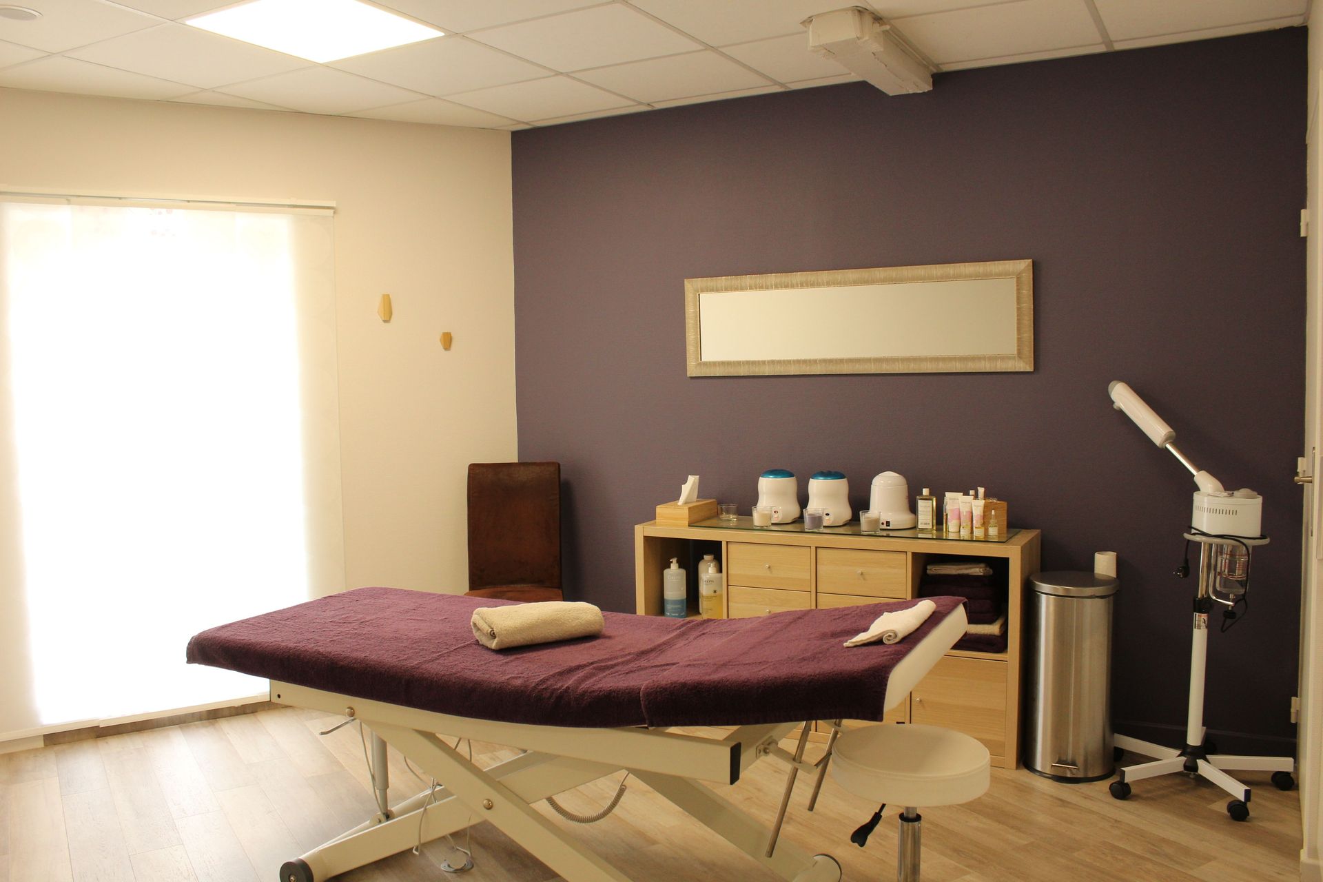 Une table de massage dans une pièce aux murs violets.