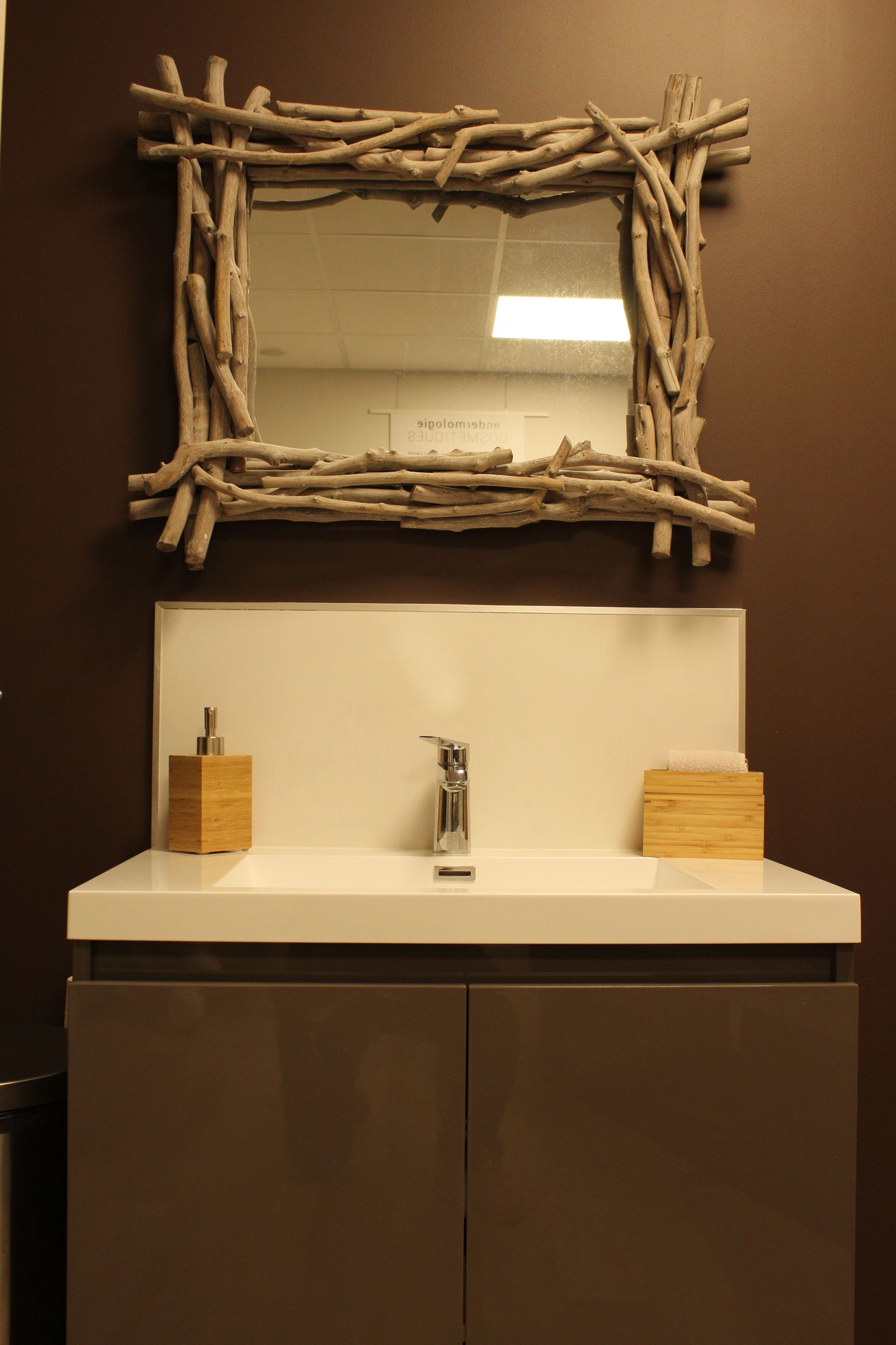 Un lavabo de salle de bain avec un miroir en bois flotté