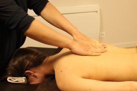 Une femme est allongée sur une table et reçoit un massage d'un homme.