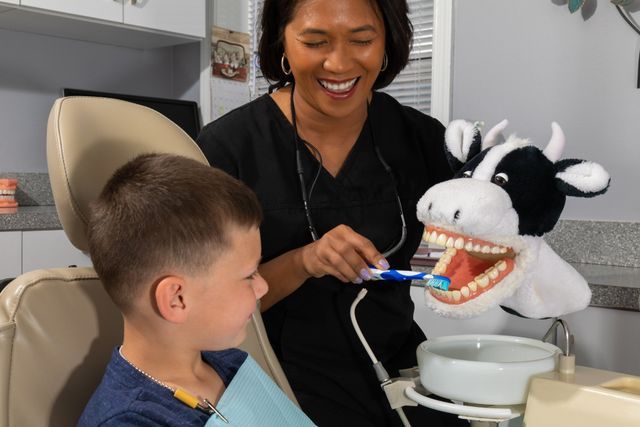 A Dentist Is Teaching A Young Boy How To Brush His Teeth — Clinton, MD — Hamam & Lamb DDS PA