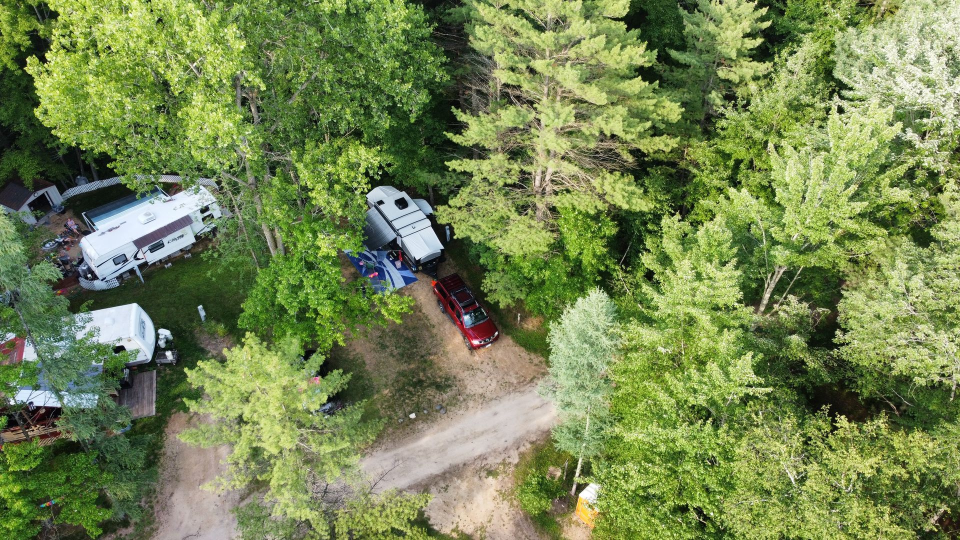 An aerial view of a rv parked in the middle of a forest.