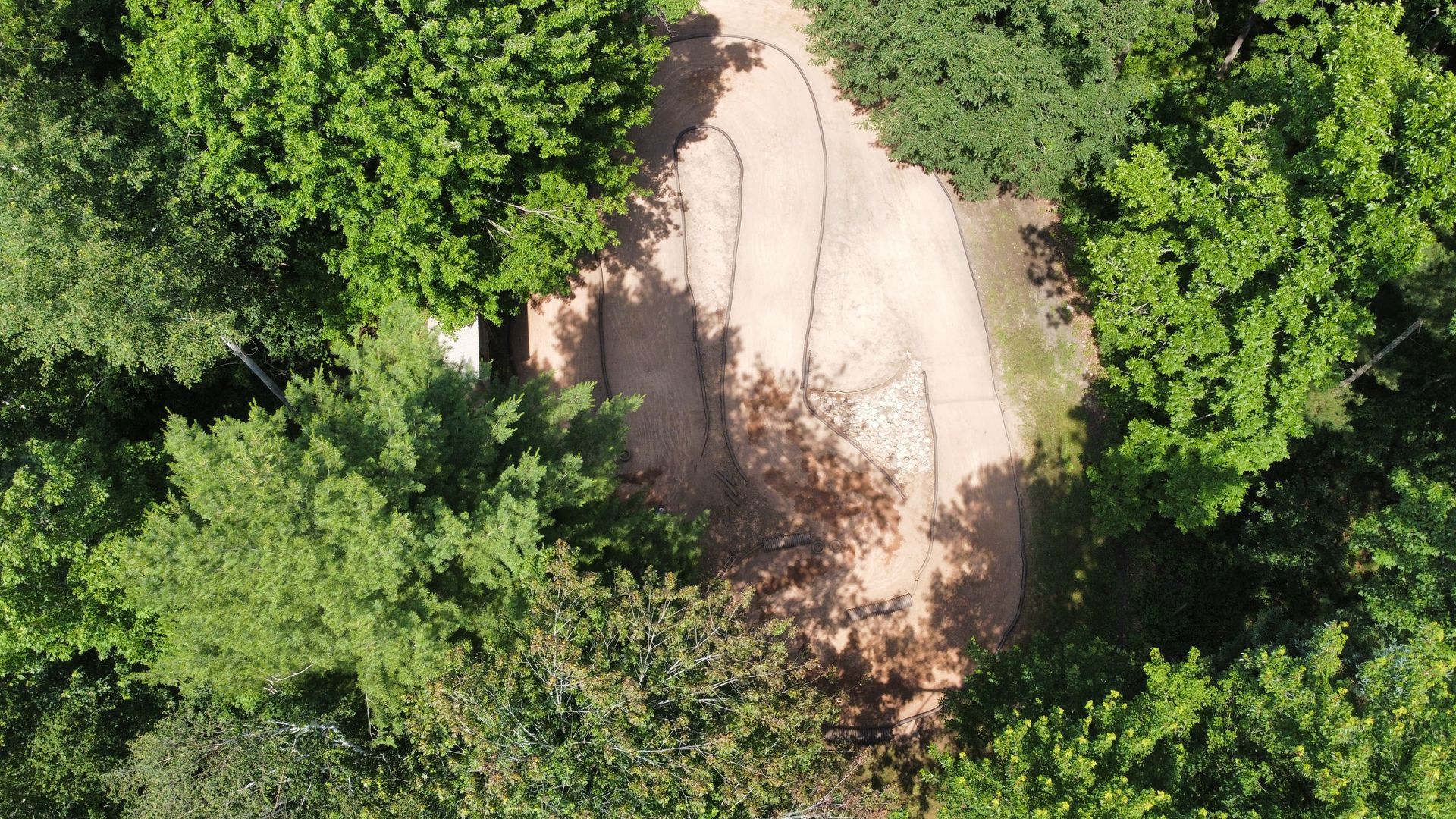 An aerial view of a dirt road in the middle of a forest.