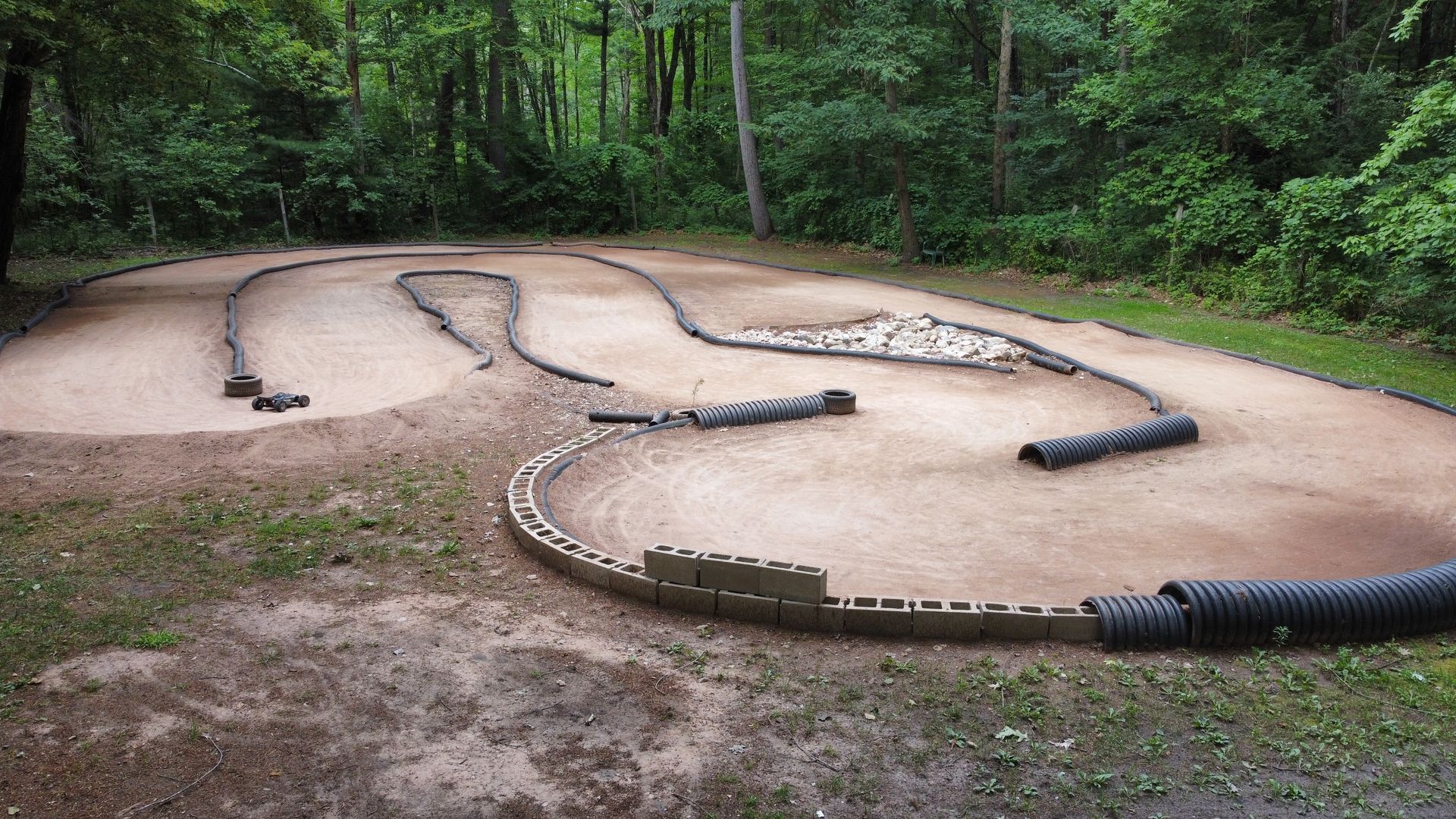 A dirt track in the middle of a forest with trees in the background