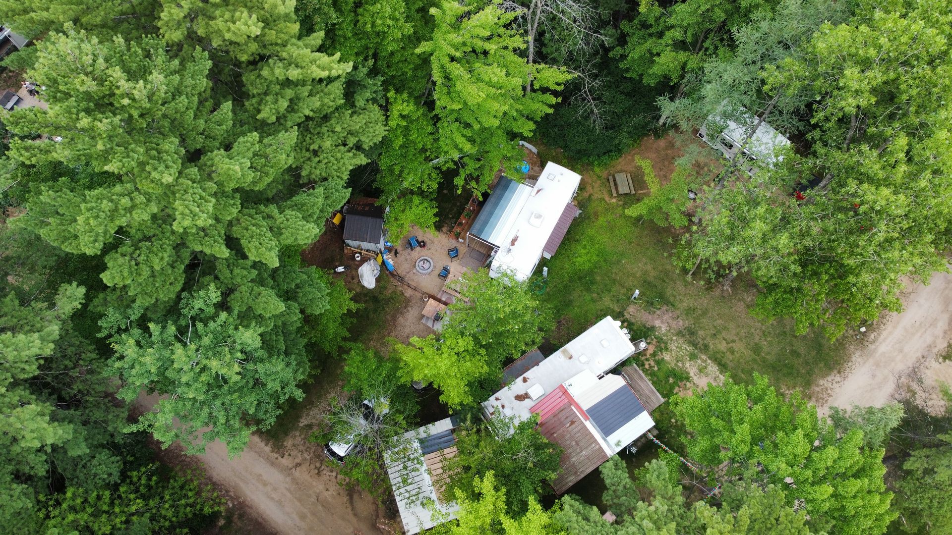 An aerial view of a small house in the middle of a forest.