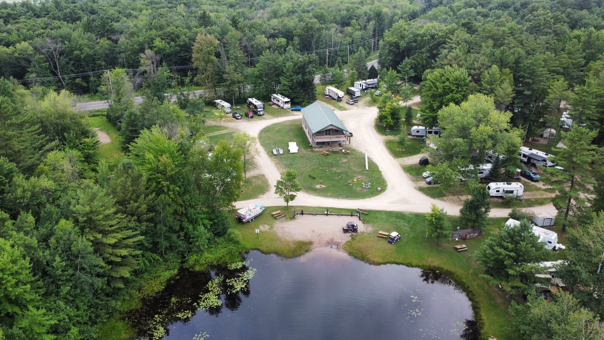 An aerial view of a campground surrounded by trees and a lake.