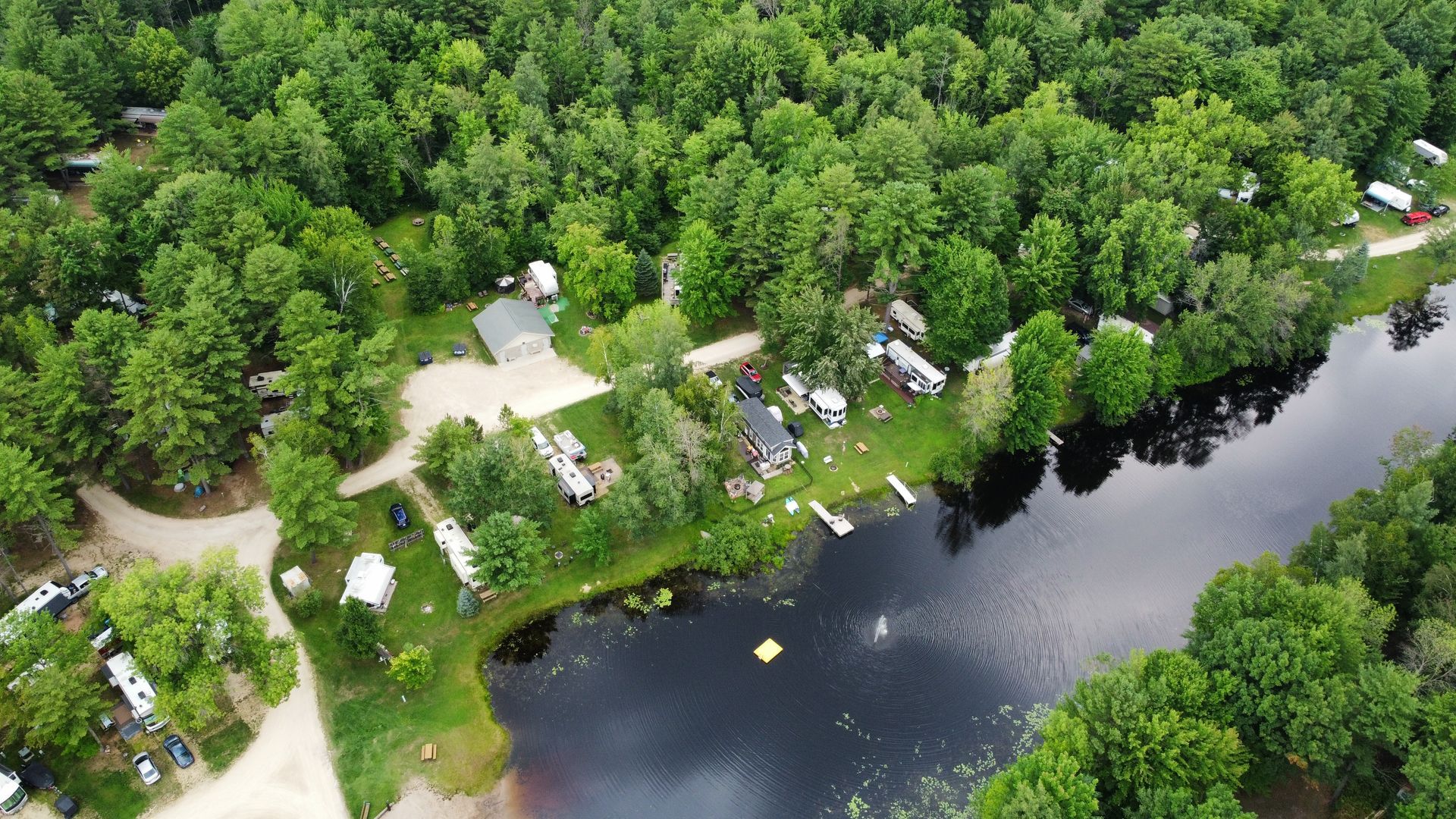 An aerial view of a campground surrounded by trees and a lake.