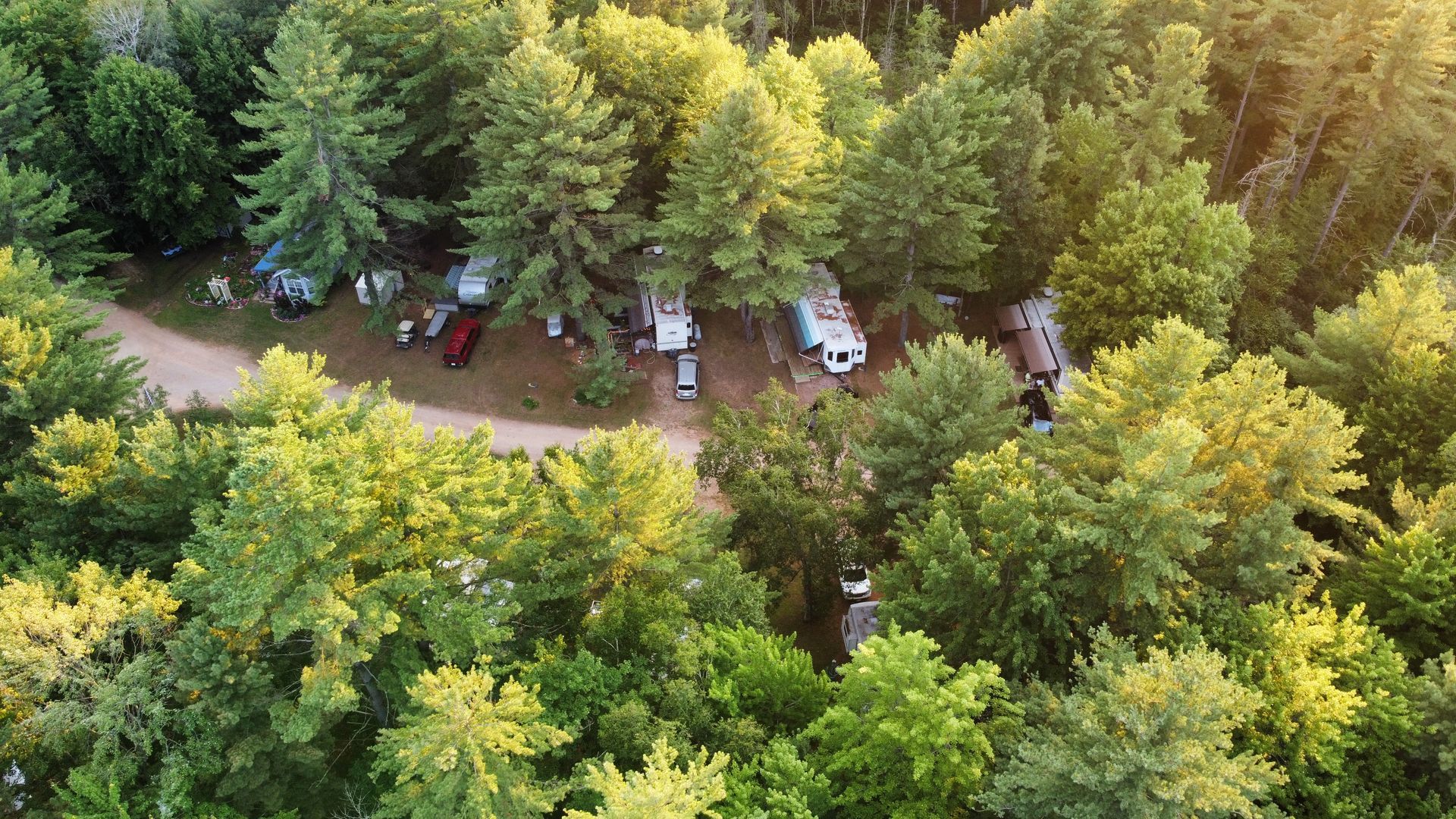An aerial view of a campground surrounded by trees and a dirt road.