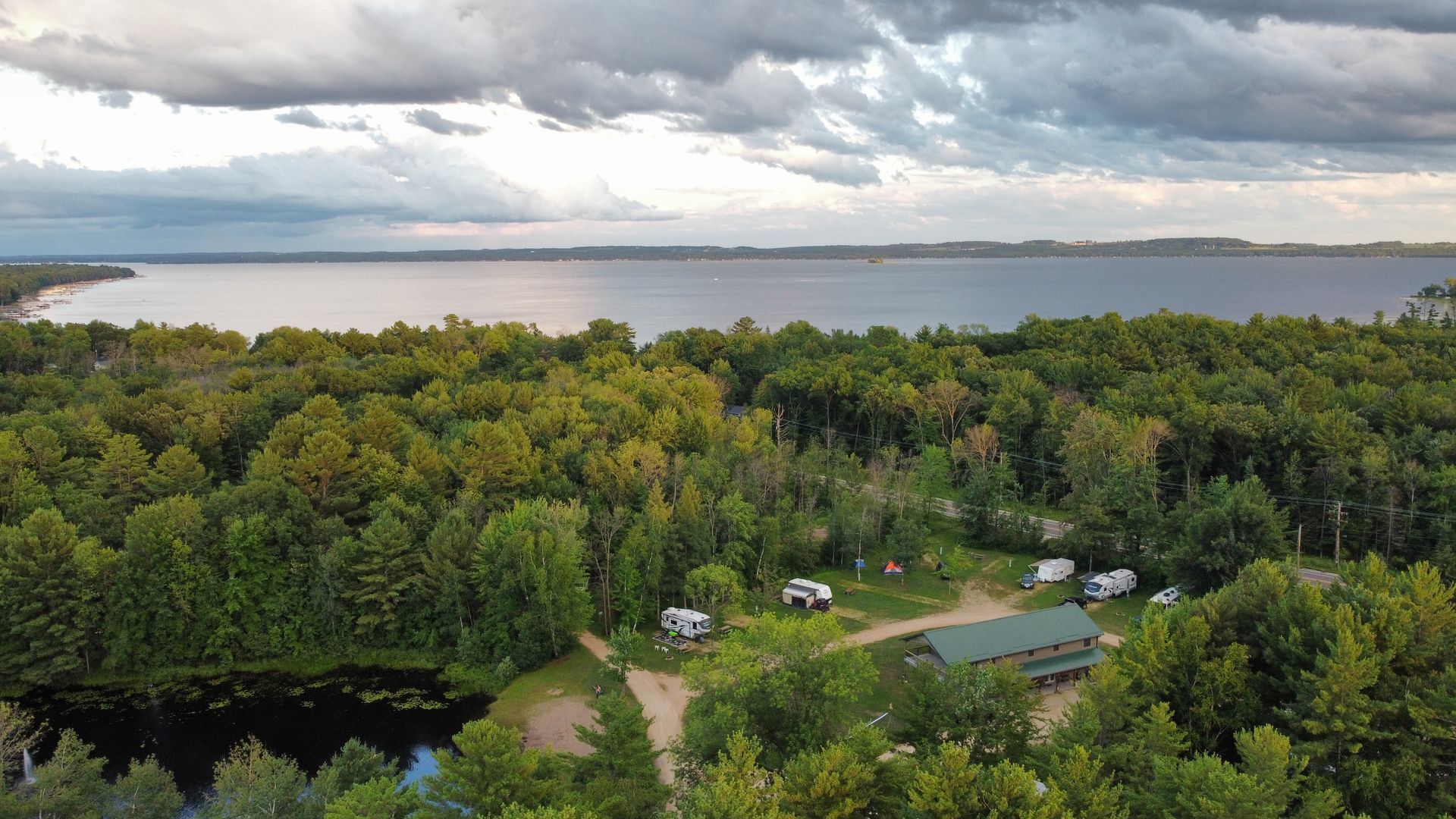 An aerial view of a campground surrounded by trees and a lake.