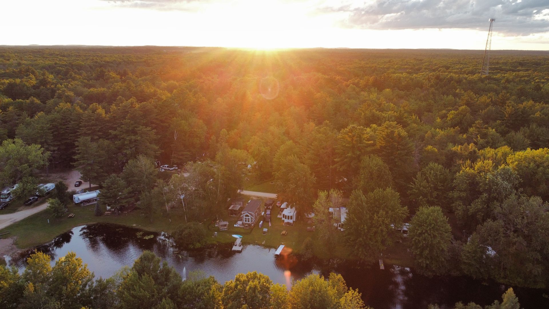 An aerial view of a lake in the middle of a forest at sunset.