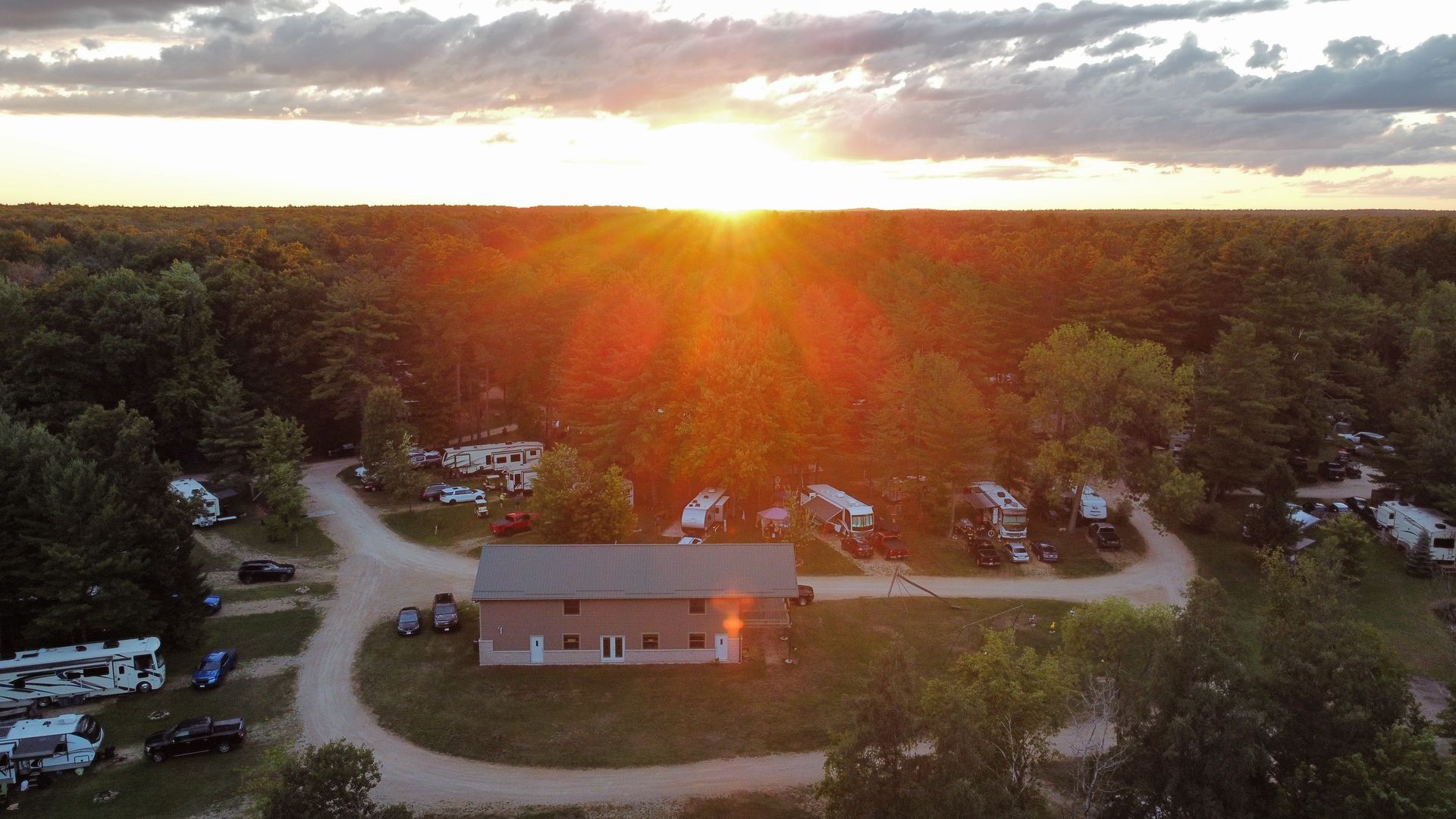 An aerial view of a campground with a house in the middle of it at sunset.