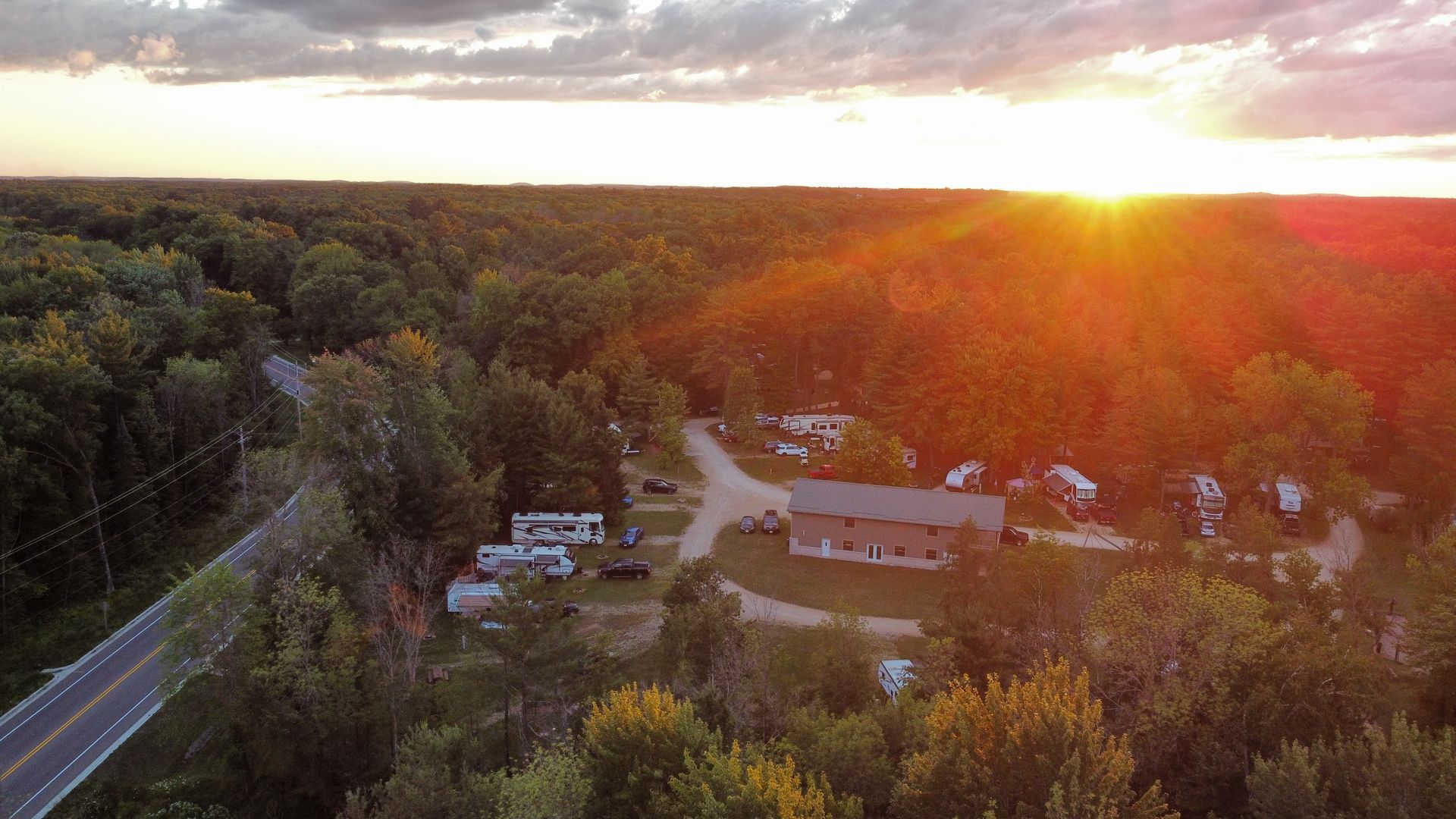 An aerial view of a sunset over a small town surrounded by trees and a road.