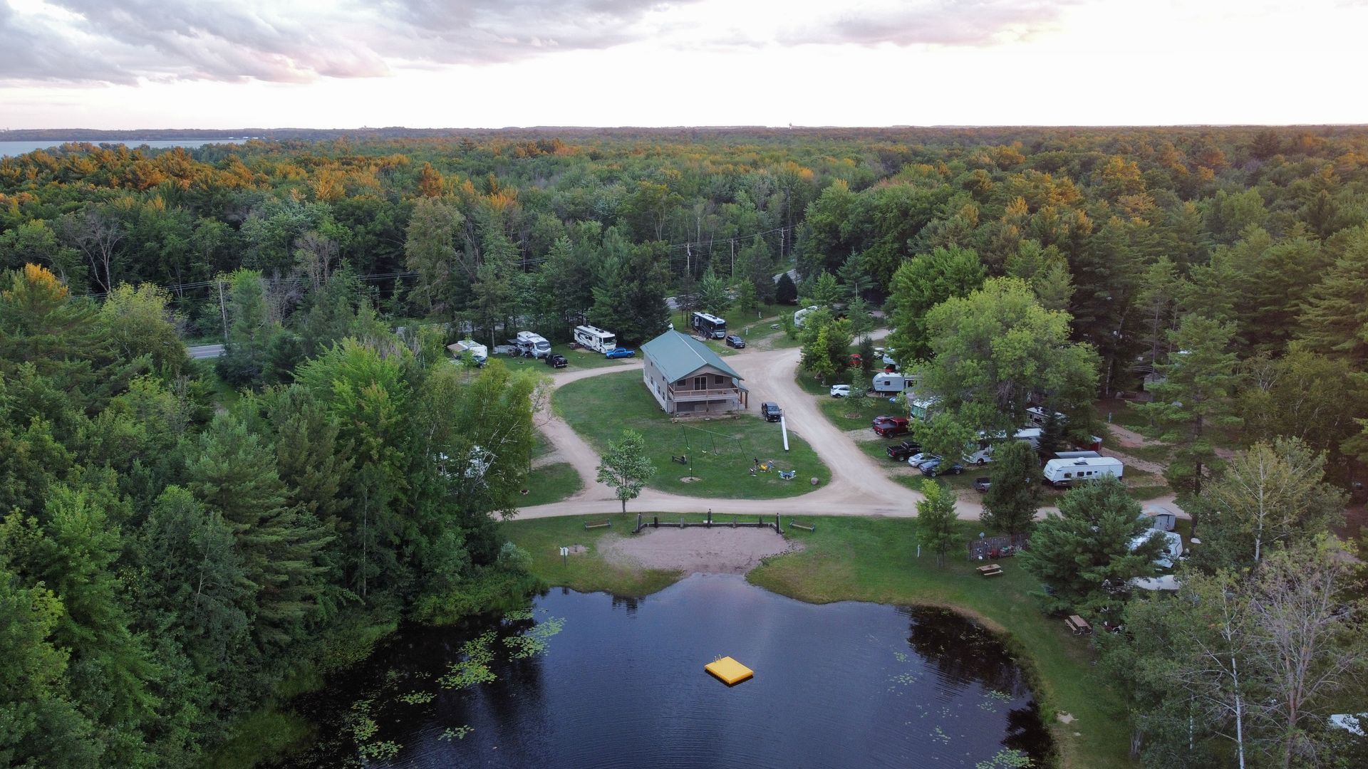 An aerial view of a campground surrounded by trees and a lake.