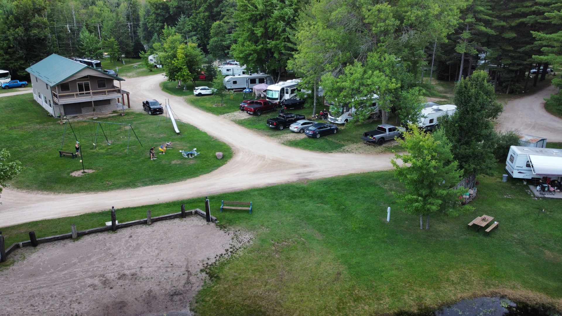 An aerial view of a campground with a lot of vehicles parked in the grass.