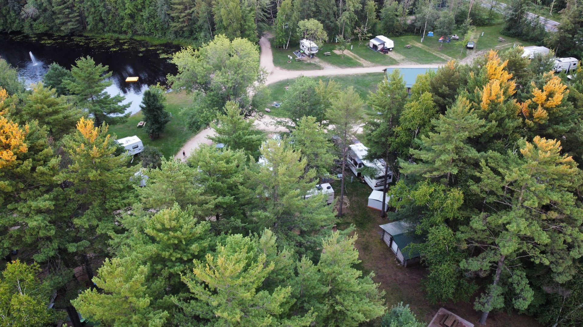 An aerial view of a campground surrounded by trees and a river.