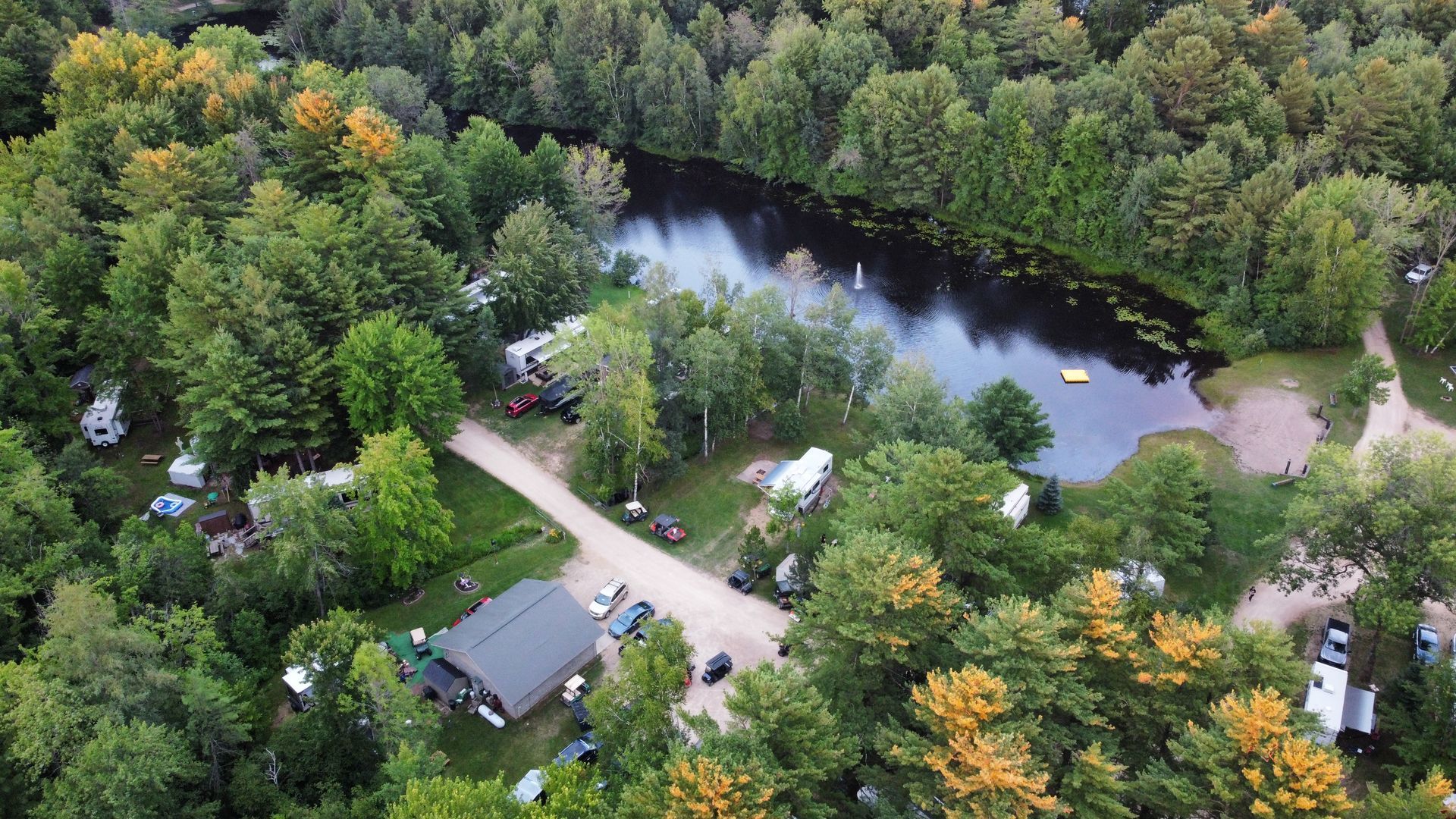 An aerial view of a campground with a lake in the middle of the woods.
