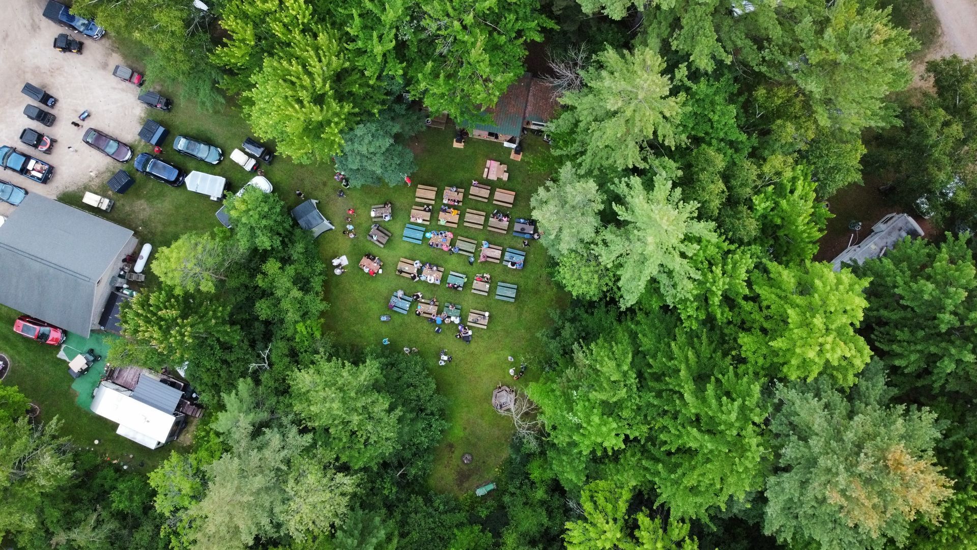 An aerial view of a group of people sitting in a field surrounded by trees.